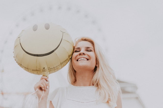 mulher sorridente segurando um balão de emoji feliz